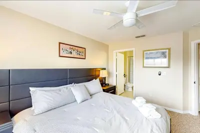 a bedroom with a large white bed with a ceiling fan at 4 Bedroom 3 Bathroom Villas At SevenDwarfs 12-108 in Kissimmee