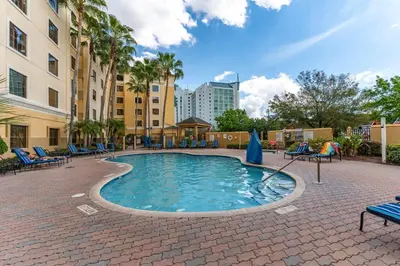a pool with chairs and umbrellas in a courtyard at Cozy Orlando Getaway with Pool Access in Orlando