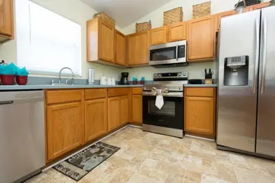 a kitchen with wooden cabinets and stainless steel appliances at Indian Creek Vacation Home Close to Disney villa in Orlando