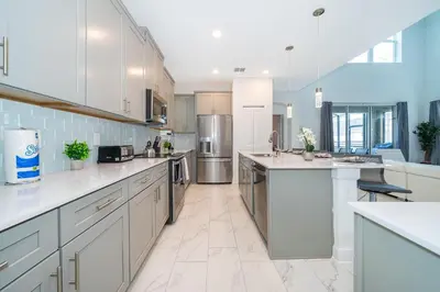 a large kitchen with white cabinets and stainless steel appliances at 4338JE VILLA 5 BED/5 BA in Kissimmee