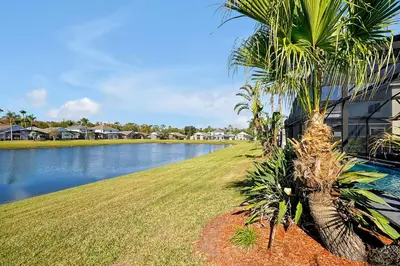 a palm tree next to a body of water at Lake Berkley Home: Pool, Lakefront & near Disney in Kissimmee