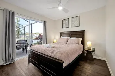 a bedroom with a large bed and a balcony at Lake Berkley Home: Pool, Lakefront & near Disney in Kissimmee