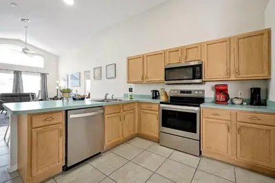 a kitchen with wooden cabinets and a stove top oven at Lake Berkley Home: Pool, Lakefront & near Disney in Kissimmee