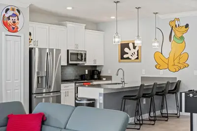 a kitchen with white cabinets and a kitchen with a blue couch at Lakeview 5BR with Game Room and Pool, Near Disney in Kissimmee