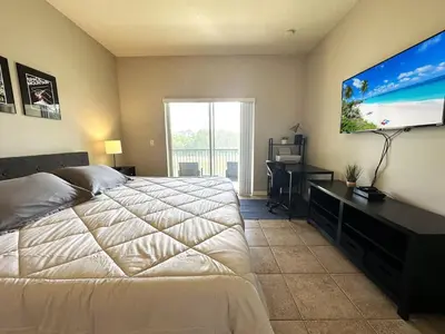 a bedroom with a bed and a desk and a flat screen tv at Amazing! Disney 7 Min, Walmart 1 min, 3 Bed 2 bt in Orlando