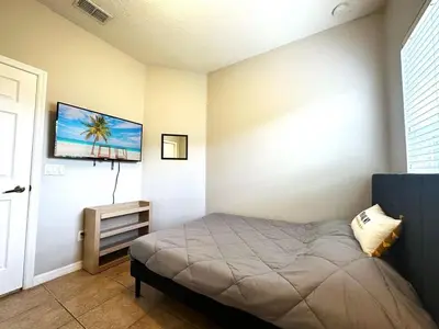 a bedroom with a bed and a tv on the wall at Amazing! Disney 7 Min, Walmart 1 min, 3 Bed 2 bt in Orlando