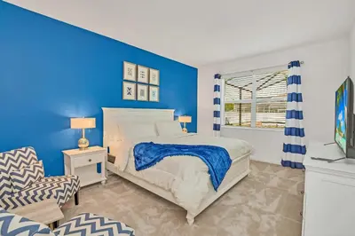 a blue bedroom with a bed and a chair at Home w Pool & Games Room Near Disney -Pet Friendly in Kissimmee