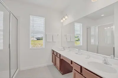 a white bathroom with two sinks and a shower at Home w Pool & Games Room Near Disney -Pet Friendly in Kissimmee