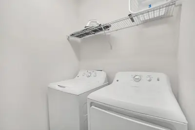 a white laundry room with a washing machine and a drying rack at Home w Pool & Games Room Near Disney -Pet Friendly in Kissimmee