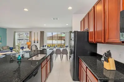 a kitchen with black counter tops and a dining room at Home w Pool & Games Room Near Disney -Pet Friendly in Kissimmee
