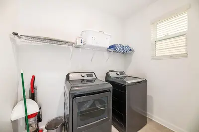 a laundry room with a stove and a washer and dryer at Spacious 6 Bed Home with Pool in Prime Storey Lake Location in Kissimmee