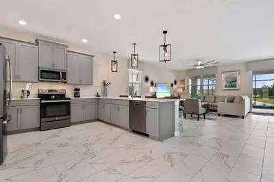 a large kitchen with stainless steel appliances and a living room at 9 Bed Home Pool Best Location Storey Lake in Kissimmee