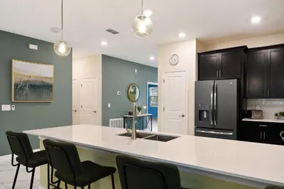 a kitchen with a large white counter and black appliances at 9 Bed Home Themed Rooms Pool Storey Lake in Kissimmee