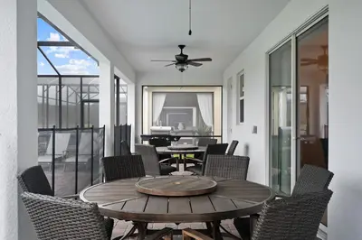 a patio with a wooden table and chairs at 9 Bed Home Themed Rooms Pool Storey Lake in Kissimmee