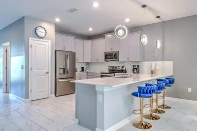 a kitchen with white cabinets and blue bar stools at 2852 Ultimate Retreat for your family 9 Bedrooms in Kissimmee