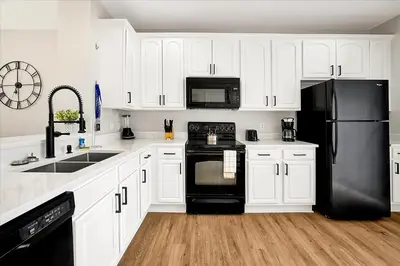 a kitchen with white cabinets and black appliances at Epic Universe New Beautiful Townhome - 4033 in Orlando