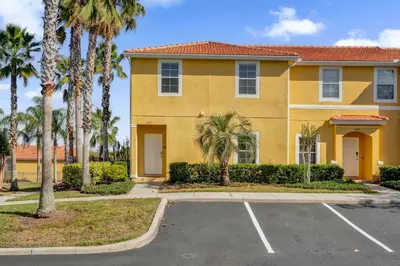 a yellow house with palm trees and a parking lot at Upstay Spacious 3BR Home w Resort Access in Kissimmee