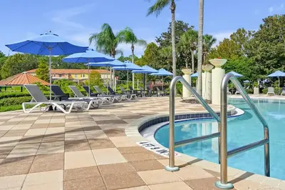 a pool with chairs and umbrellas at a resort at Upstay Spacious 3BR Home w Resort Access in Kissimmee
