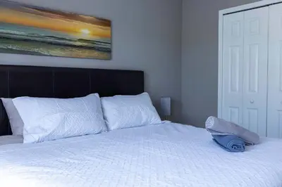 a bedroom with a white bed with a painting on the wall at Cozy Family 3BR Townhouse Perfect Stay for 6 Guests in Kissimmee
