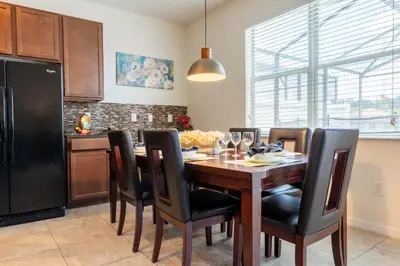 a kitchen with a wooden table and black chairs at Luxury 4 bedroom 3 bath pool Home 283 in Kissimmee