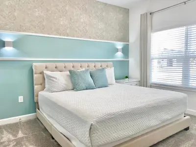 a bedroom with a large bed with blue walls and a window at Beautiful 4 bedroom 3 bath pool Townhome 280 in Kissimmee