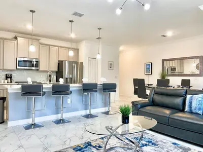 a living room with a couch and a kitchen at Luxury 4 bedroom 3 bath pool Home 264 in Kissimmee