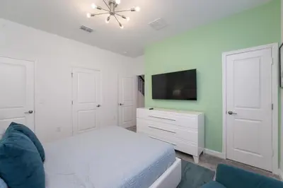 a bedroom with a bed and a flat screen tv at Luxury 4 bedroom 3 bath pool Home 271 in Kissimmee