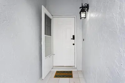 a hallway with a white door and a rug at APluSS Getaway in Kissimmee