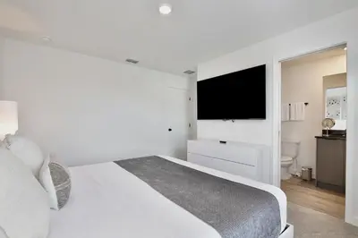 a white bedroom with a bed and a flat screen tv at Brand new townhouse in The Hub in Kissimmee