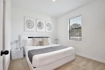 a white bedroom with a white bed and a window at Brand new townhouse in The Hub in Kissimmee