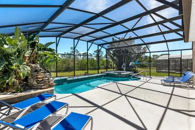 a swimming pool with a pergola and blue chairs at Luxury Emerald Island Resort Villa with Stunning Pool Deck and Lake View Near Disney in Kissimmee