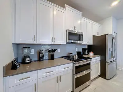 a kitchen with white cabinets and a black refrigerator at Incredible Family Retreat with PS5 Private Pool and access to 2 Clubhouses in Kissimmee