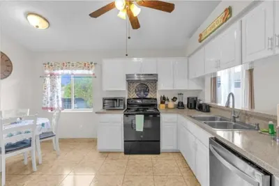 a kitchen with white cabinets and a stove top oven at Cozy Home Near Disney With Private Pool in Kissimmee