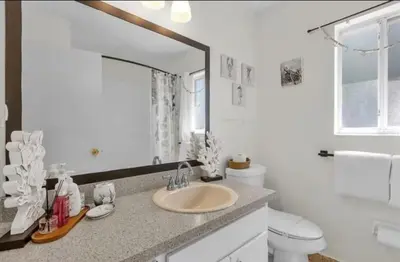 a bathroom with a sink and a toilet and a mirror at Cozy Home Near Disney With Private Pool in Kissimmee