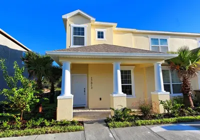 a yellow house with columns and palm trees at 17413 Luxury Pool Villa Serenity Haven, 3BR, Balcony in Orlando