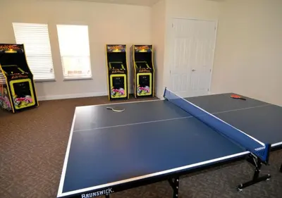 a ping pong table in a room with four video games at 17413 Luxury Pool Villa Serenity Haven, 3BR, Balcony in Orlando