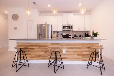 a kitchen with white cabinets and a counter with stools at 2604 - Luxury 4-BR Villa with Private Pool Retreat in Kissimmee