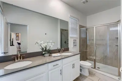 a bathroom with two sinks and a shower and a toilet at 2940 - Elegant 5BR Villa at Storey Lake Resort Comfort Luxury and Proximity Disney and Universal in Kissimmee