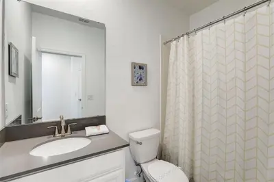 a bathroom with a sink and a toilet and a mirror at 2940 - Elegant 5BR Villa at Storey Lake Resort Comfort Luxury and Proximity Disney and Universal in Kissimmee