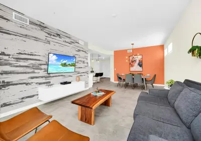 a living room with a couch and a tv on a wall at Luxury 3-Bed Condo in Storey Lake Resort - 3131 in Kissimmee