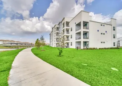 a white apartment building with a green lawn at Luxury 3-Bed Condo in Storey Lake Resort - 3131 in Kissimmee
