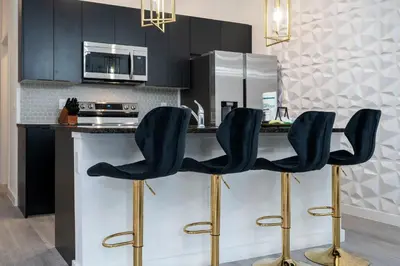 a kitchen with black cabinets and gold bar stools at Luxury 3 Bed Home up to 8 guests- The Hub - 3236 TT in Orlando