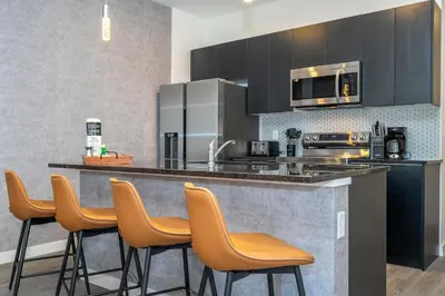 a kitchen with a bar with chairs and a counter top at 3258 SW - Luxury Getaway The Hub Relax and Enjoy a Serene Vacation Retreat in Kissimmee
