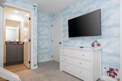 a bedroom with a tv on a wall with blue clouds at 3258 SW - Luxury Getaway The Hub Relax and Enjoy a Serene Vacation Retreat in Kissimmee