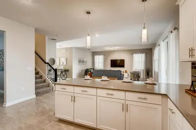 a kitchen with white cabinets and a living room at Stunning 6BR Home, Private Pool & Spa - 14 Guests - 4507 NL in Kissimmee