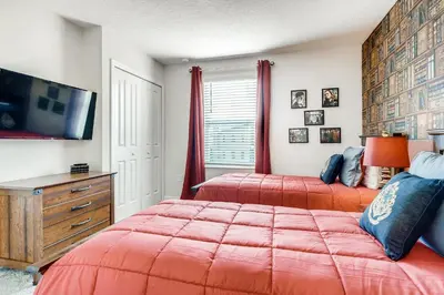 two beds in a bedroom with red comforter at Stunning 6BR Home, Private Pool & Spa - 14 Guests - 4507 NL in Kissimmee