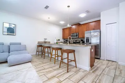 a kitchen with a bar with stools and a couch at 4812 BR - Enchanted Lakeside Escape Luxurious Family Retreat in Kissimmee