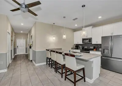 a kitchen with white cabinets and a bar with chairs at Stunning Townhome with Private Pool - Storey Lake - 5021 WW in Kissimmee