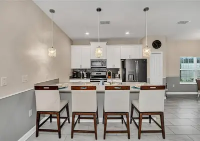 a kitchen with white cabinets and a island with chairs at Stunning Townhome with Private Pool - Storey Lake - 5021 WW in Kissimmee