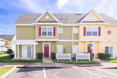 a yellow house with a white fence in a parking lot at 4562 YR Amazing in Kissimmee